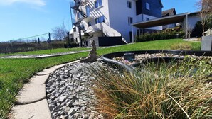 Ein gepflegter Gartenbereich mit Kiesweg, einem kleinen Springbrunnen und einer Statue.