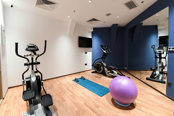 A gym with exercise equipment, a blue mat, and a purple exercise ball. - Holiday Inn Express Tianjin Binhai by IHG (Tianjin)