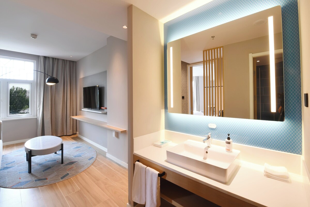 A modern bathroom with a large mirror, a sink, and a toilet.