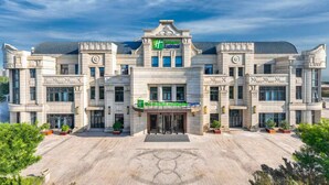 A large, ornate hotel with a central entrance, multiple wings, and a landscaped courtyard. - Holiday Inn Express Tianjin Binhai by IHG (Tianjin)