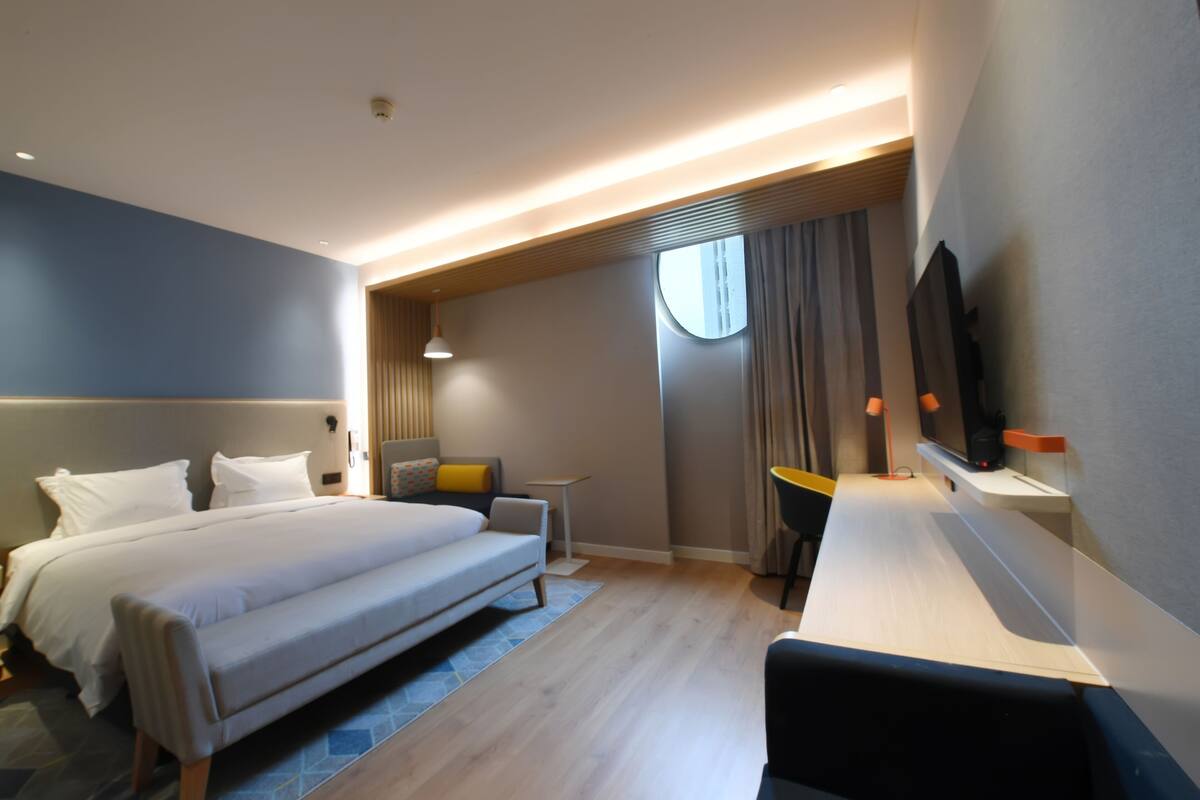 A modern hotel room with two beds, a desk, and a TV.