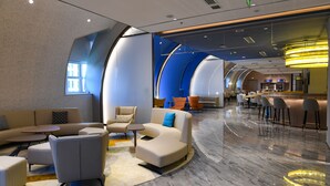 A modern hotel lobby with a curved seating area, a reception desk, and a bar/lounge area. - Holiday Inn Express Tianjin Binhai by IHG (Tianjin)