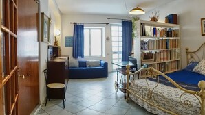 A room with a bed, a desk, a chair, a bookshelf, and a window with curtains. - Apartment (Santa Teresa Gallura)