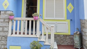 A two-story building with a balcony, a staircase, and potted plants. - Apartment (Santa Teresa Gallura)