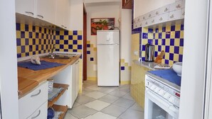 A narrow kitchen with a refrigerator, sink, and stove. - Apartment (Santa Teresa Gallura)