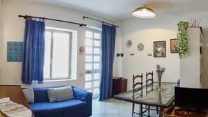 A living room with a blue sofa, a glass dining table, and a TV. - Apartment (Santa Teresa Gallura)