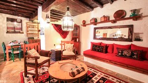 A cozy living room with a red sofa, wooden chairs, a round coffee table, and a hanging light fixture. - Dandy Villas Amfiklia (Amfikleia-Elateia)