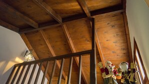 A wooden staircase with a railing, wooden beams, and a wall-mounted light fixture. - Dandy Villas Amfiklia (Amfikleia-Elateia)