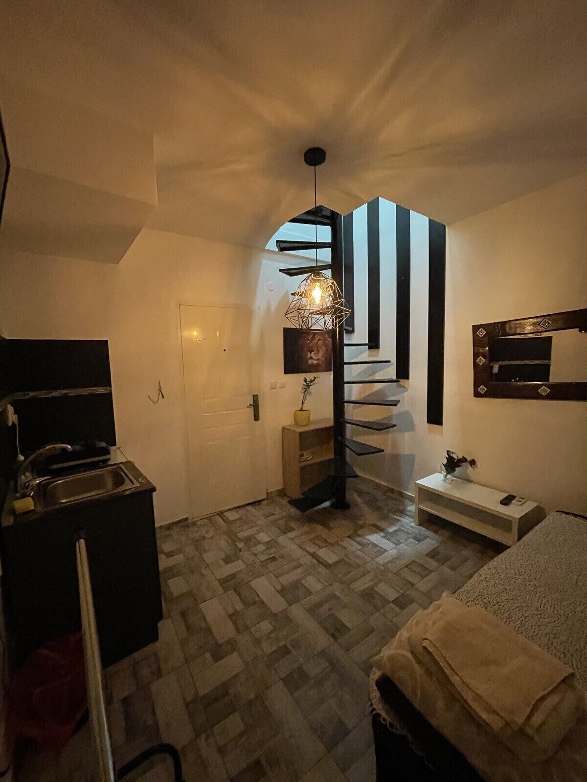 A modern interior with a staircase, a kitchen area, and a seating area with a TV.
