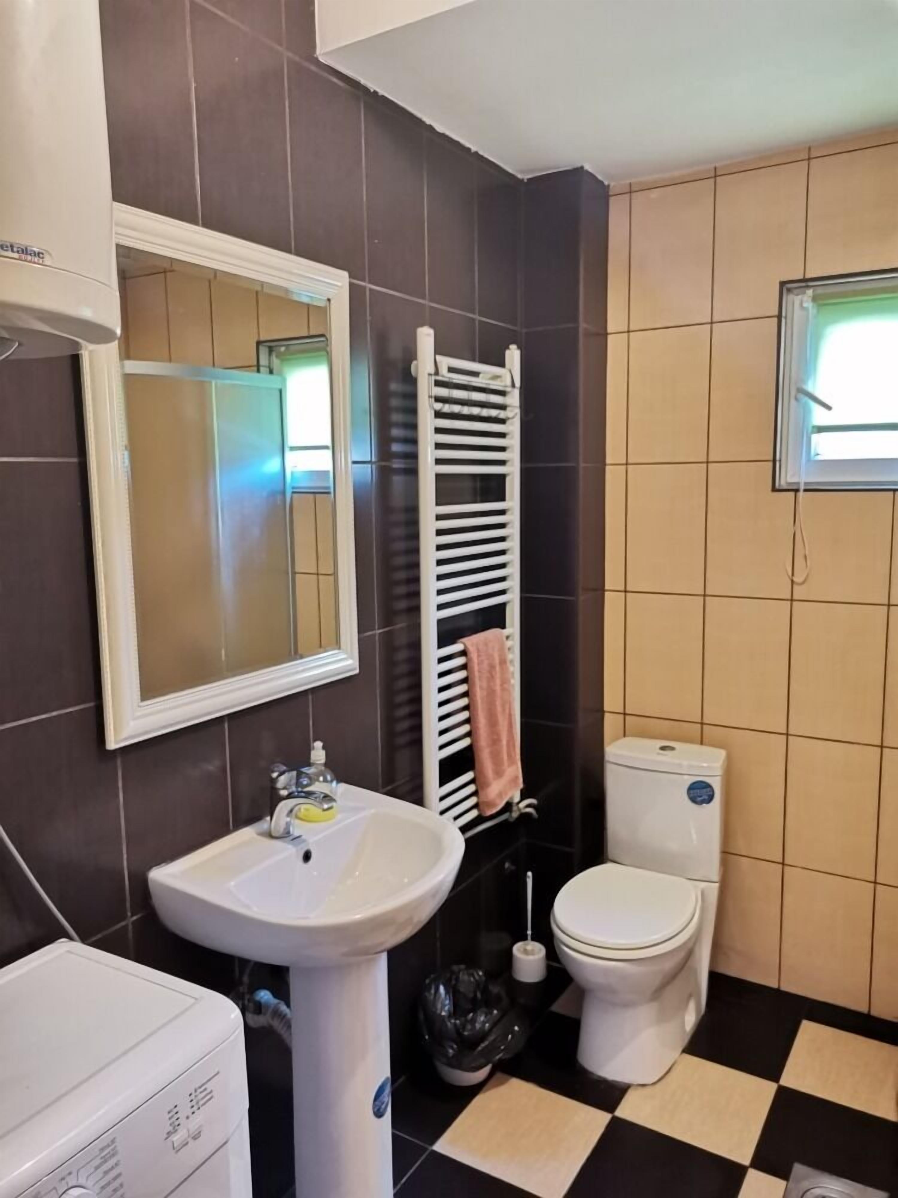 Un baño con lavamanos blanco, espejo, inodoro y perchero.