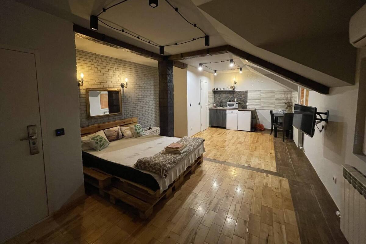 A compact, modern apartment with a loft-style bedroom, a kitchenette, and a dining area.