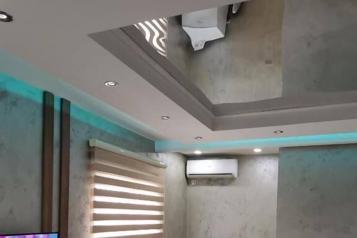 A modern bedroom with a bed, a TV, and an air conditioning unit.