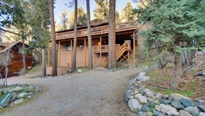 Une cabane avec une allée en gravier, une terrasse en bois et un escalier menant à l’étage supérieur.