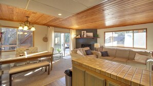 Un vaste espace de vie doté d’un plafond en bois, d’une table à manger avec des chaises, d’un canapé et d’un comptoir de cuisine.