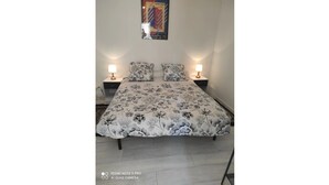 Um quarto com colcha florida, duas mesas de cabeceira com abajures e um pôster na parede.
