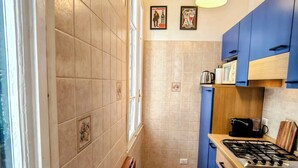 Eine Küche mit blauen Schränken, einem Gasherd, einer Mikrowelle und einer Pendelleuchte.