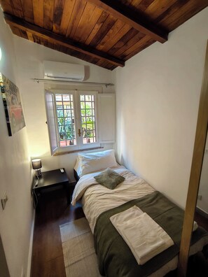 Ein Schlafzimmer mit Bett, Nachttisch, Lampe, Fenster mit Blick und Deckenventilator.