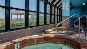 A hot tub area with tiled walls and a window view.