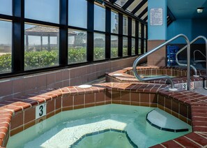 Un espace dédié à un bain à remous, avec des murs carrelés et une fenêtre donnant sur l’extérieur.