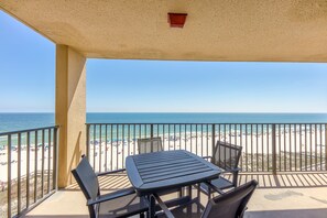 Ein Balkon mit Tisch und Stühlen mit Blick auf einen Strand.