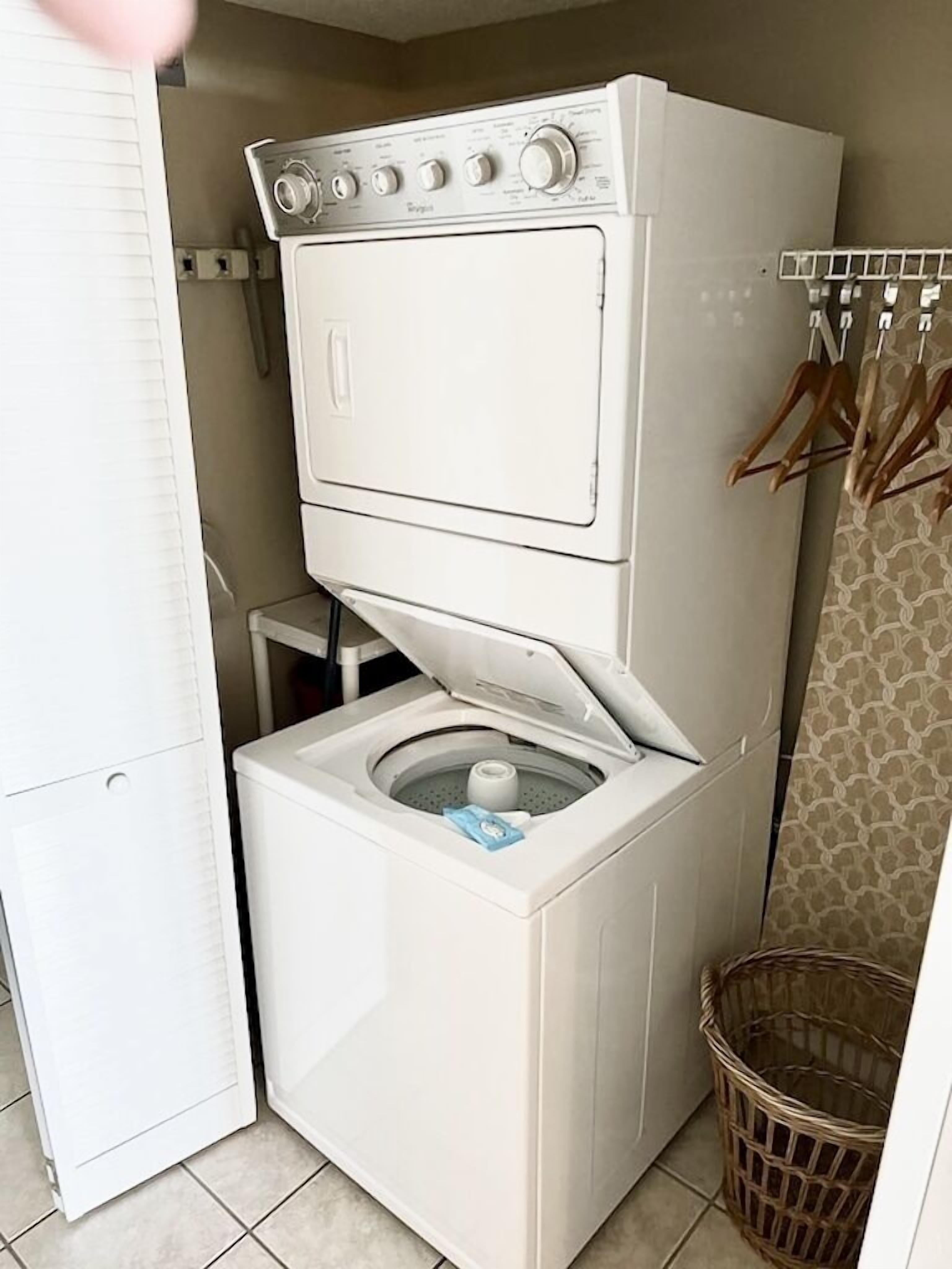 A compact laundry room with a front-loading washer and dryer stacked vertically.