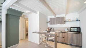 A modern kitchen with a wooden countertop, two white bar stools, and a built-in microwave. - WePuglia - Dimore Stefania - Suite Viuzza (Polignano a Mare)