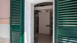 A doorway with green shutters, leading to a hallway with a staircase. - WePuglia - Dimore Stefania - Suite Viuzza (Polignano a Mare)