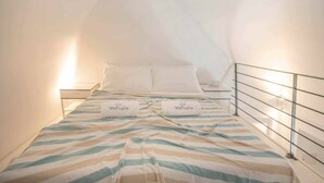 A single bed with striped bedding and two pillows labeled 'WePuglia.' - WePuglia - Dimore Stefania - Suite Viuzza (Polignano a Mare)