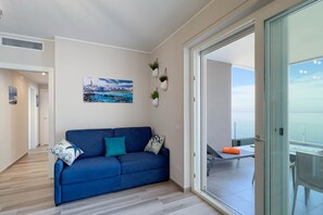 A modern living room with a blue sofa, a cityscape painting, and potted plants. - WePuglia - Dimora Adriatica (Monopoli)