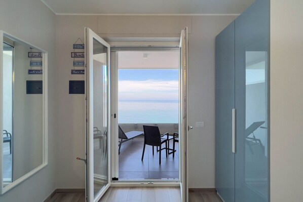 Et værelse med en skydedør, der fører ud til en balkon med havudsigt.