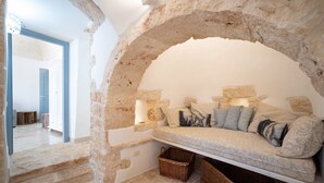 Um quarto aconchegante com um arco de pedra, um banco acolchoado com almofadas e cestos de vime.