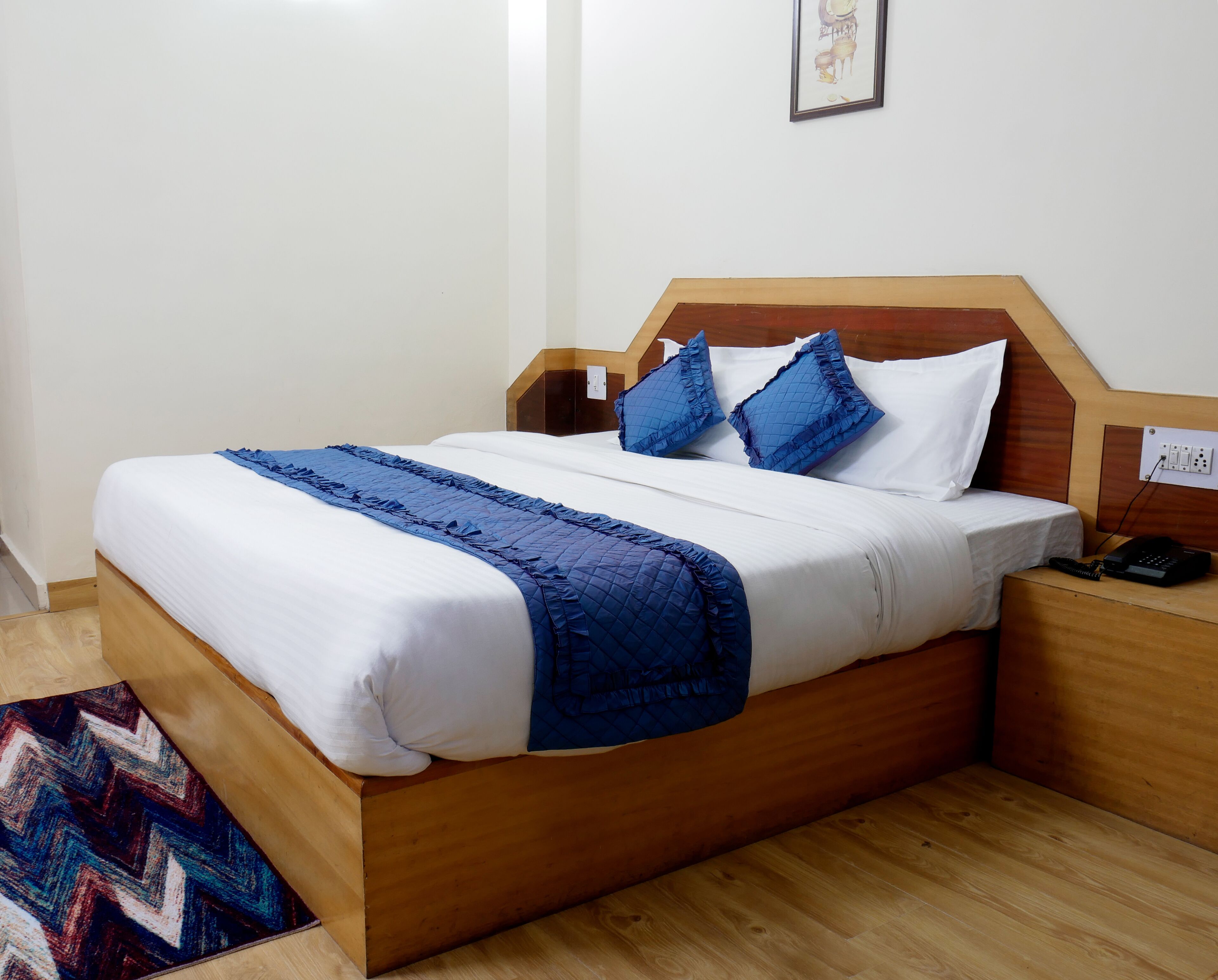 Una cama bien hecha con cabecera de madera, ropa de cama blanca y detalles en azul.
