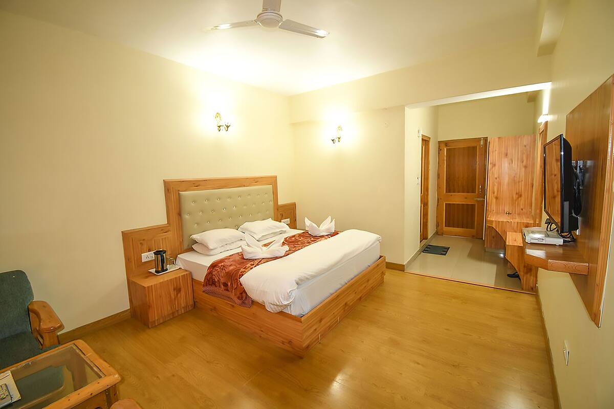 A bedroom with a wooden bed, nightstands, a mirror, and a television.