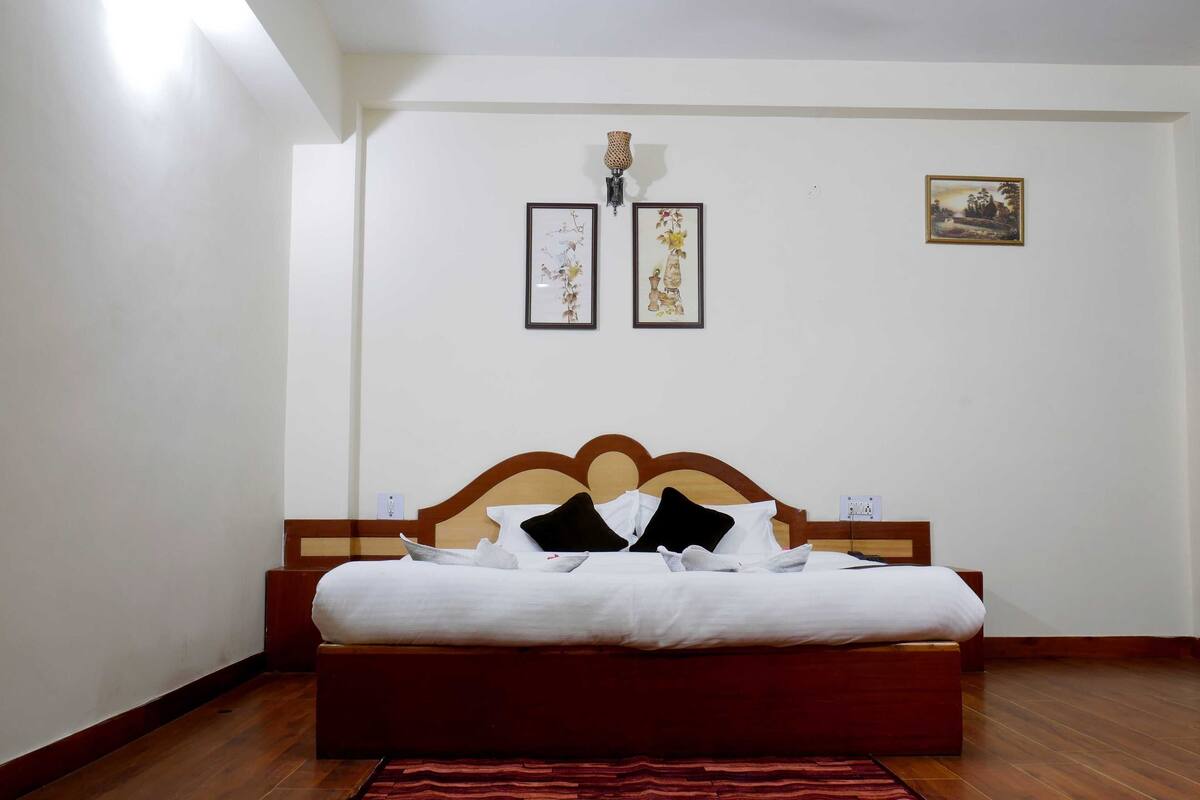 A neatly made bed with a wooden headboard in a room with white walls and a wooden floor.