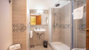Un baño moderno con cabina de ducha de vidrio, un lavamanos y un perchero para toallas.