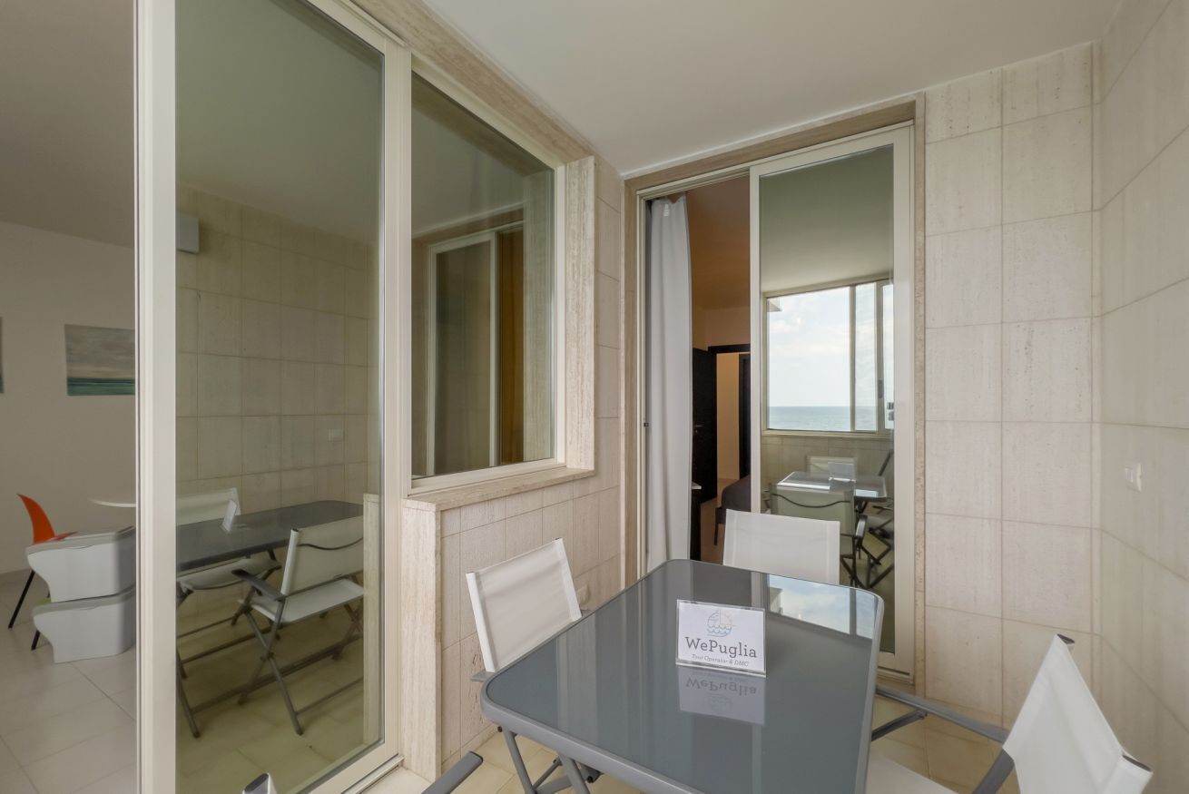 A conference room with a glass table, white chairs, and a sign reading 'WePuglia.'