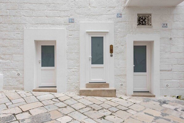 Three white doors with numbers 11, 13, and 9 on a white stone wall.
