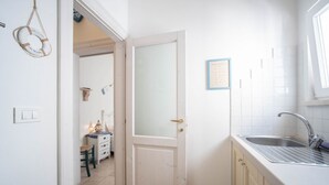 Una cocina con puerta blanca, un lavamanos y un certificado enmarcado en la pared.