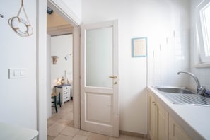 Uma cozinha com porta branca, pia e um certificado emoldurado na parede.