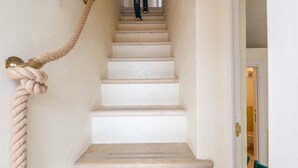 Una escalera con barandilla de cuerda y una puerta que da a una habitación.