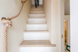 A staircase with a rope handrail and a door leading to a room.
