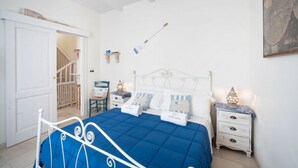 Un dormitorio con cama, mesitas de noche, un mapa y una puerta que da a otra habitación.