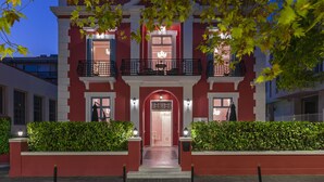 Un edificio rojo con una entrada central, dos balcones y una fachada bien iluminada.