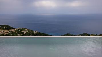 Una piscina al aire libre, sombrillas, sillones reclinables de piscina