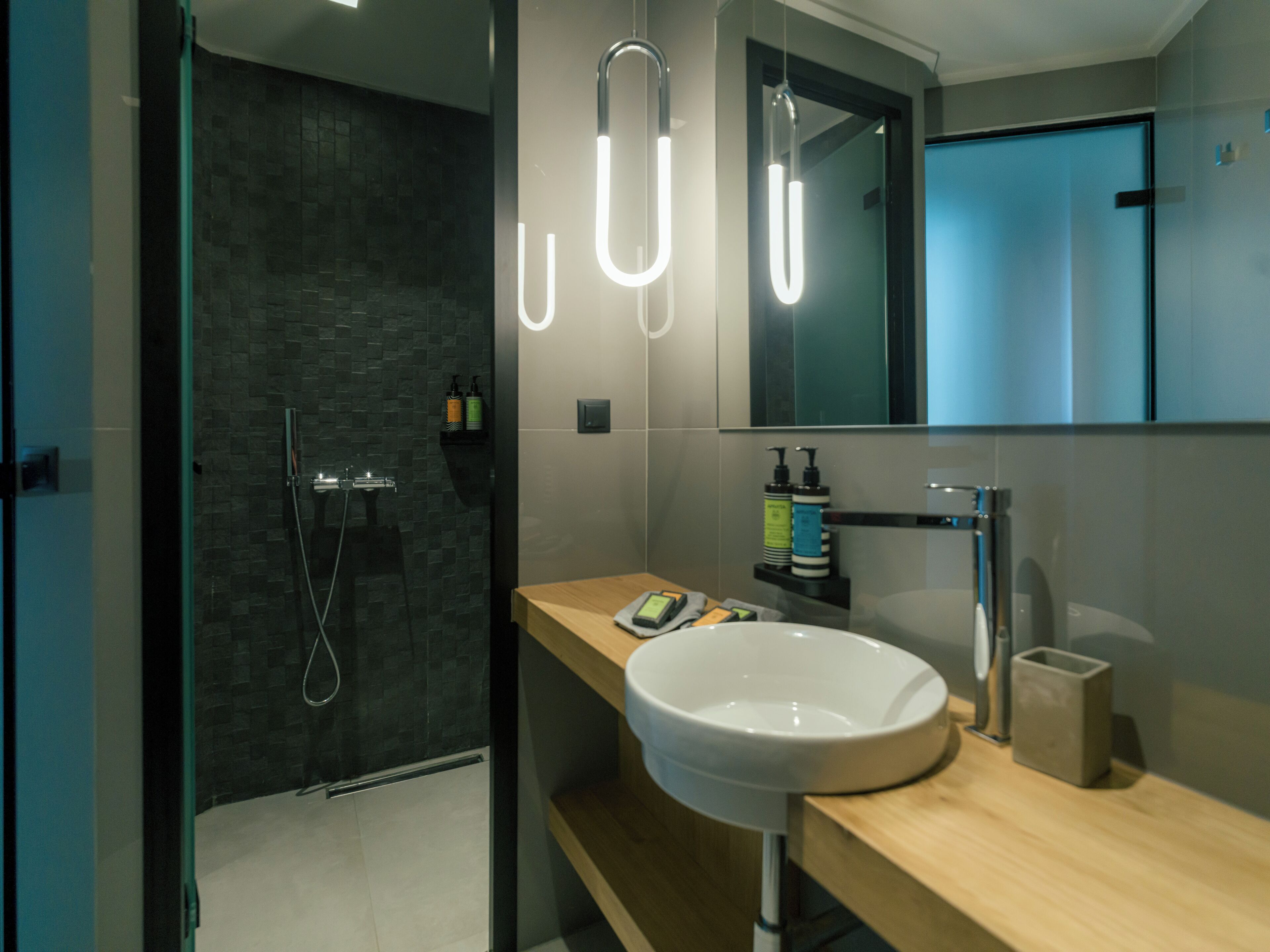 A modern bathroom with a glass-enclosed shower, a white sink, and a wooden vanity.