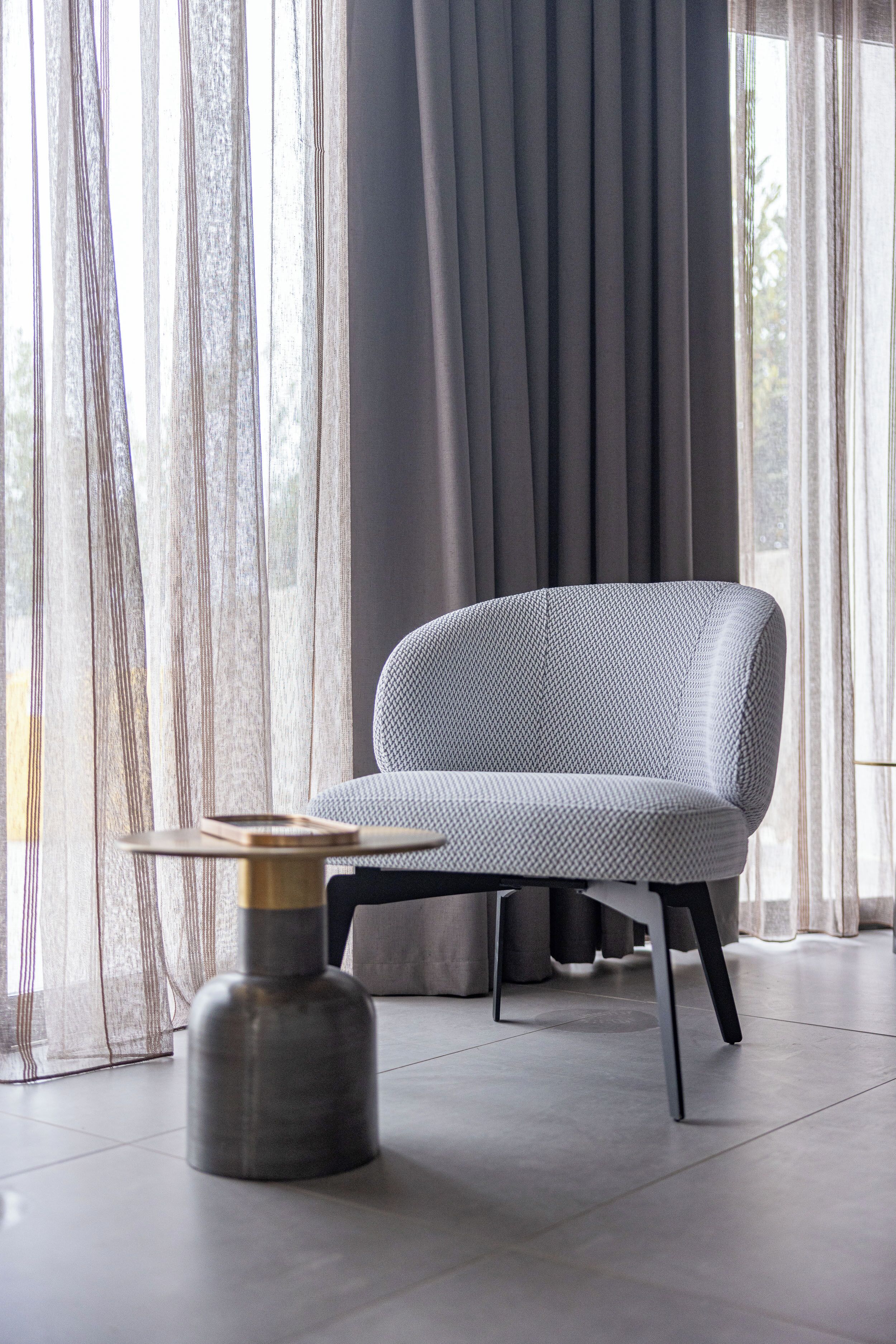 A modern living room with a grey upholstered sofa, a small round table, and a metallic vase.