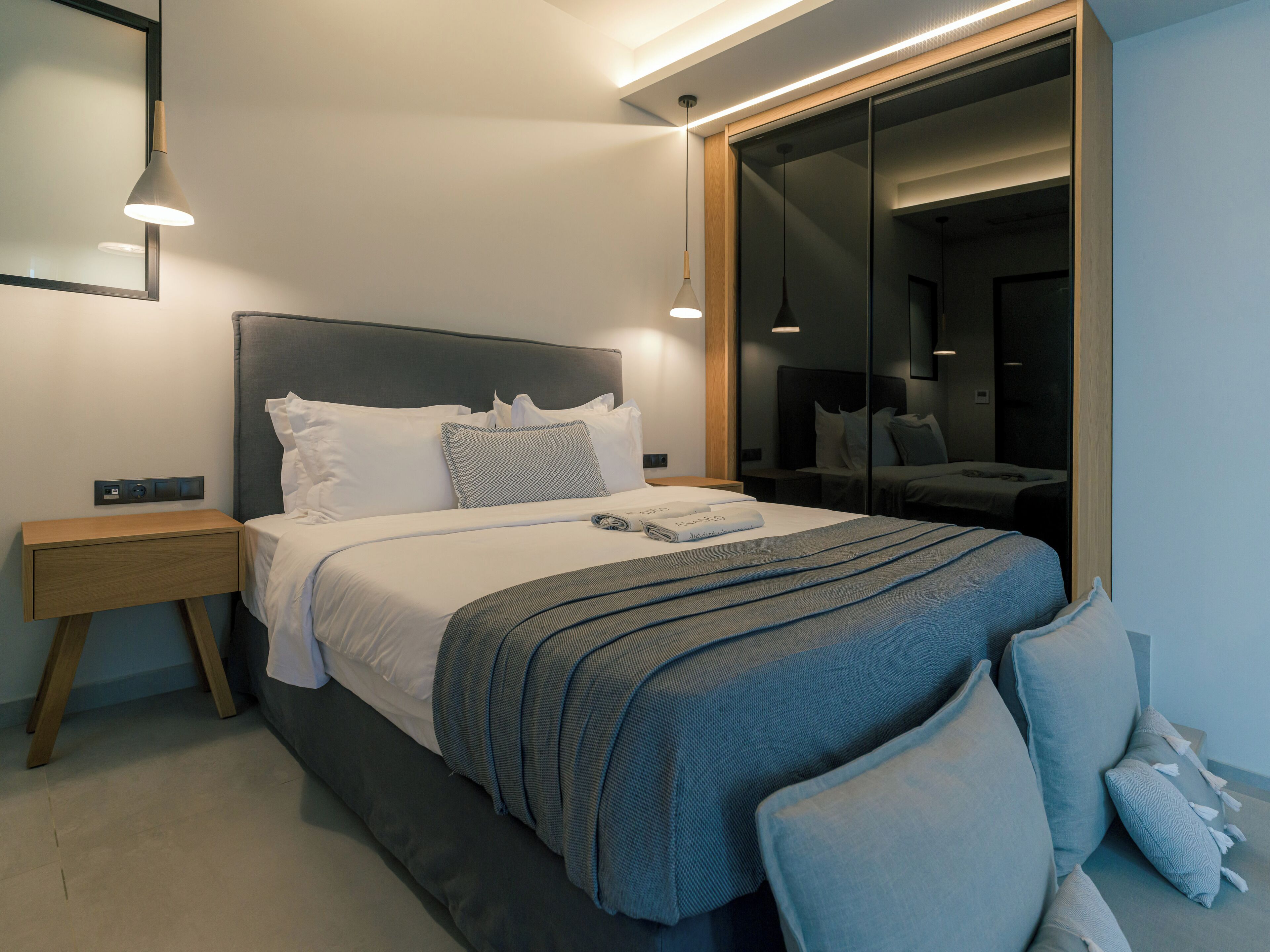 A modern bedroom with a bed, bedside tables, and a large mirror.