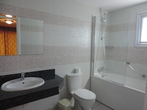 A bathroom with a sink, toilet, and glass-enclosed shower.