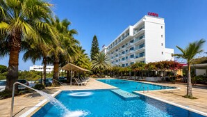 Un hotel con piscina, palmeras y un edificio con la palabra 'CORFU' en el techo.