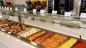 Un bufé con diversas opciones de comida, incluyendo huevos, tocino, huevos revueltos y frijoles horneados.